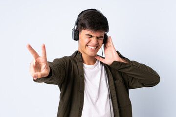 Handsome man over isolated blue background listening music and singing