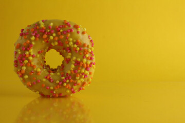 donut bagel in yellow glaze on bright yellow background with place for text there is room for a copyspace for cafes. No diet day