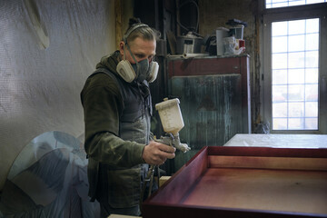 close-up Man using protective gloves painting wooden timber with spray paint gun. spray gun getting paint over timber.