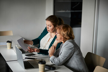 New female worker asking business lady for help with document
