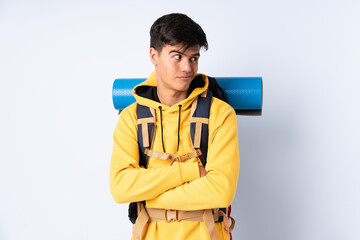 Young mountaineer man with a big backpack over isolated blue background thinking an idea