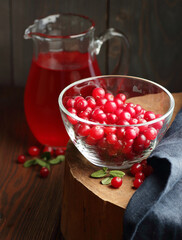 Cranberry cold drink in glass pitcher with red berries on wooden rustic background, closeup, winter christmas holiday drinks, healthy healing liquids, natural medicine and naturopathy concept