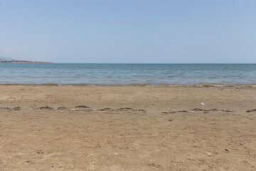 Plain sand beach landscape on a blue sky with low tide water and empty sand