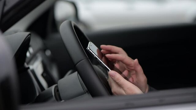 Woman using mobile phone for text messaging in car, close up of female hand and smartphone device