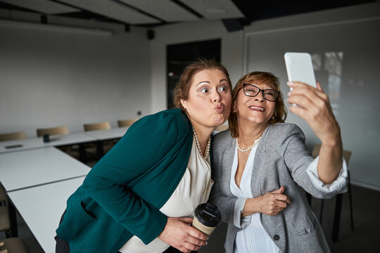 Funny employee and supervisor taking selfie in office
