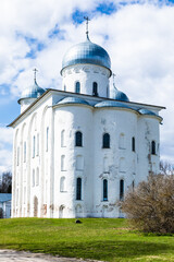 Yuriev Monastery in Veliky Novgorod town, Russia - May 02 2021: oldest Russian monastery in sunny spring day on background of blue sky with clouds on hill with green grass