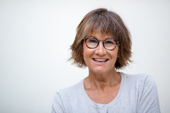 Close up older woman laughing with eyeglasses against white background
