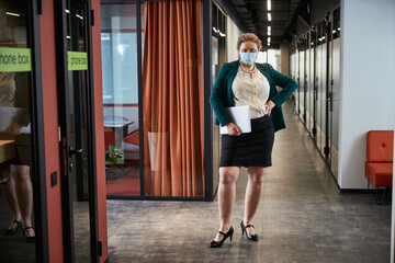 Self-assured personal assistant looking to camera in office corridor