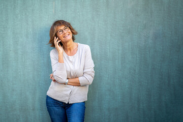 older woman talking with mobile phone by green background