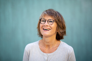 Close up happy woman with glasses laughing by green wall