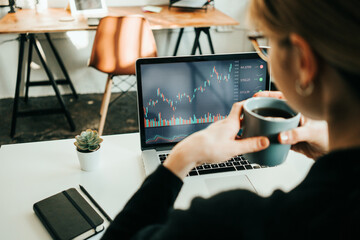 Woman working with stock market using laptop, analyzing trading data