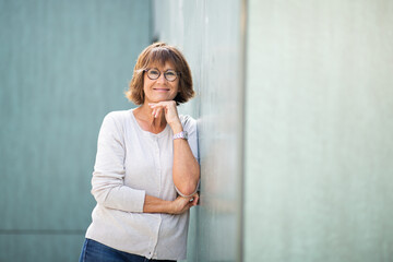 older woman leaning against wall and smiling