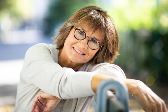 Close up happy older woman with glasses relaxing on park bench