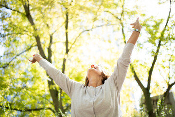 happy woman with arms outstretched in nature - Powered by Adobe