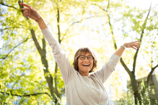 happy older woman with arms outstretched in nature