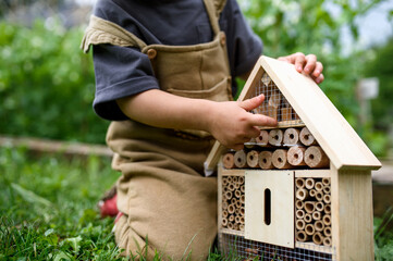 Obscured small child playing with bug and insect hotel in garden, sustainable lifestyle. © Halfpoint