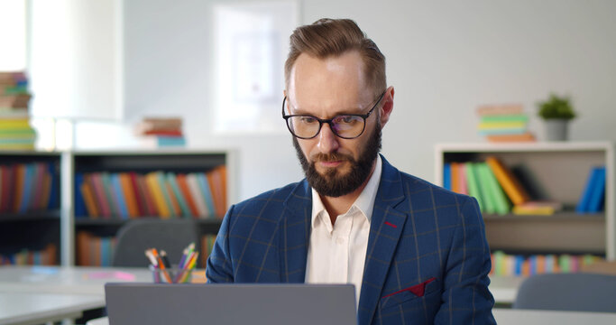 Close up portrait of school teacher typing report on laptop
