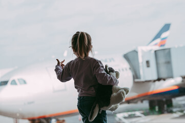 Toddler girl at airport in face mask holding a toy