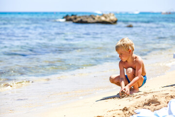 Fototapeta na wymiar boy playing in the sand on the beach