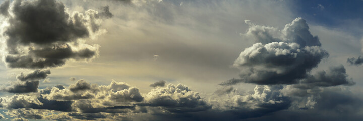 wide panoramic view of the unbelievably beautiful sky with cumulus clouds and sunlight in a light atmospheric haze