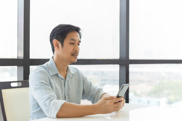 Portrait of handsome man relaxing using smart phone at home.