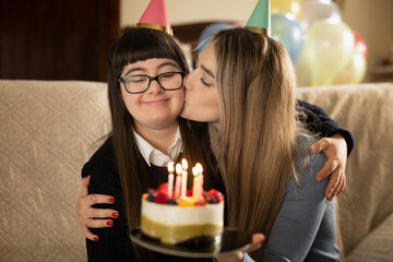 Authentic shot of happy young woman is having fun to celebrate birthday of teen sister with down...
