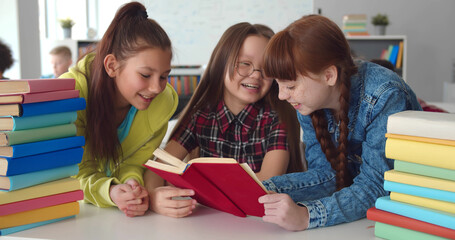 Fototapeta na wymiar Diverse kids sitting at desk and reading books in classroom