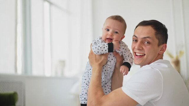 Funny Game and Laugh of Caucasian Man and Baby boy in Domestic Comfort. Young father playing with son. Father's day.