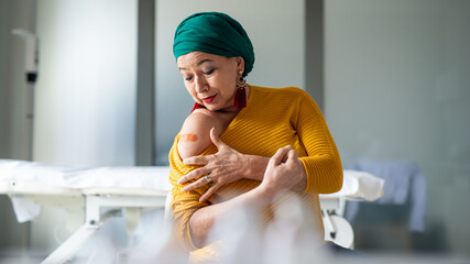Happy senior woman with head wrap after vaccination in hospital, promotion concept.