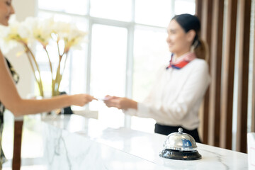 Close up bell in luxury modern reception hotel desk with the blurred reception employee receiving information from a new customer. - obrazy, fototapety, plakaty