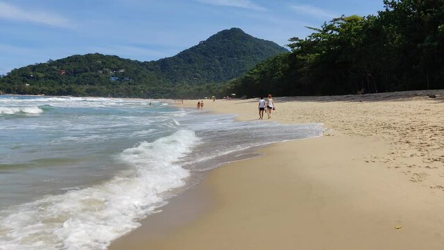 Dream beaches and tropical paradises. Waves of blue ocean on sandy beach. Ubatuba, Brazil.