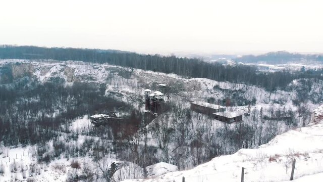 Drone footage of Liban quarry Kamieniolom Liban in Krakow, Poland during the winter season. Light snow-fall. The whole area covered with snow. Grove of trees against the clear white sky in the