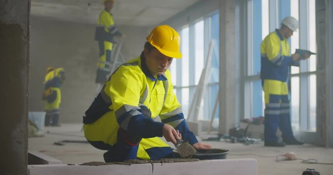 Construction worker using trowel and tools for building wall with bricks and mortar