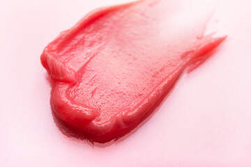 Cosmetics smear isolated on pink background. Skincare creme, lipstick or lip gloss swatch. Beauty macro texture