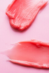 Two cosmetic smears on pink background. Creme, lipstick, lip gloss swatch macro wallpaper. Vertical banner
