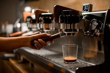 Fototapeta na wymiar barista controls lever of modern professional coffee machine that and pours coffee drink into glass