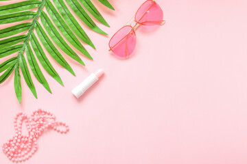 Women's fashion accessories and cosmetics of pink color isolated on pink background with palm leaf. Pink glasses. Magazines, social networks. View from above. Flat lay.