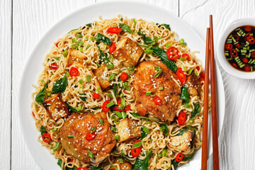 Wok noodles with chicken and tofu on a white plate
