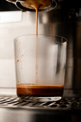 close-up on clear glass in which espresso flows from portafilter of coffee machine