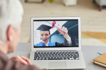 Fototapeta na wymiar Closeup of mature man watching teenage son graduating by video chat on laptop screen