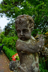 Fototapeta na wymiar A weathered cherub statue in one of many gardens of Charleston