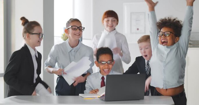 Cute multiracial children working together as team hugging and celebrating success
