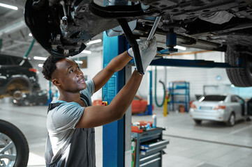 Male mechanic checks car suspension, auto service