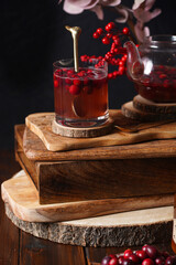 Two glasses with red cranberry tea and honey on a wooden table