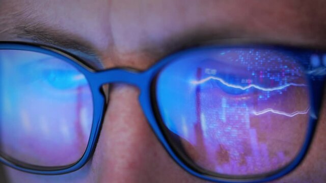 Close up view of focused businessman wearing eyeglasses analyzing data of graphs and charts in front of laptop. Online trading,stock market recession,business uptrend and downtrend, financial crisis.