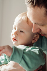 A happy father holds a baby son in his arms.Time together.Family concept.Father's Day concept.Paternal care.Newborn care.Close up,selective focus.