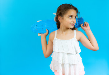 Smiling little girl with skateboard isolated over blue background