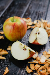 One whole apple and two quarters of sliced apple on the dark wooden table