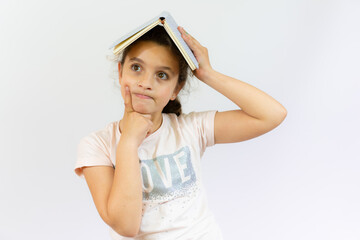 Fototapeta premium Lovely little girl standing and holding a book over white background