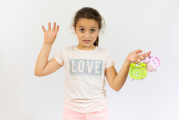 Portrait of little girl holding two alarm clocks isolated on white background